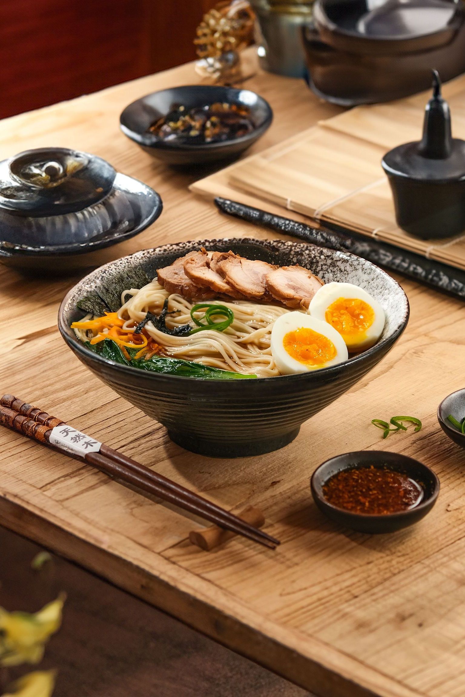 A visually appealing Japanese ramen bowl with eggs, chicken, and vegetables on a wooden table.
